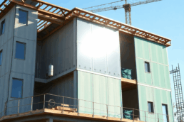 A modern building under construction with solar panels and green insulation, illuminated by natural sunlight, showcasing sustainable architecture a...